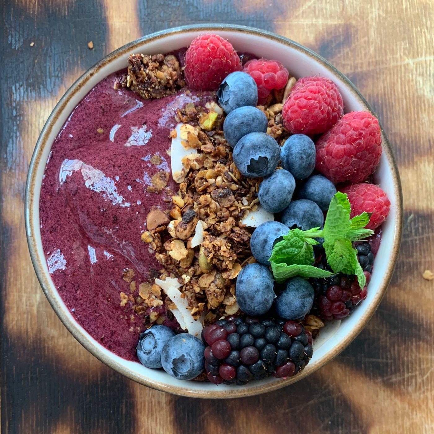 Tigela de açaí com granola, mirtilo, framboesa e hortelã